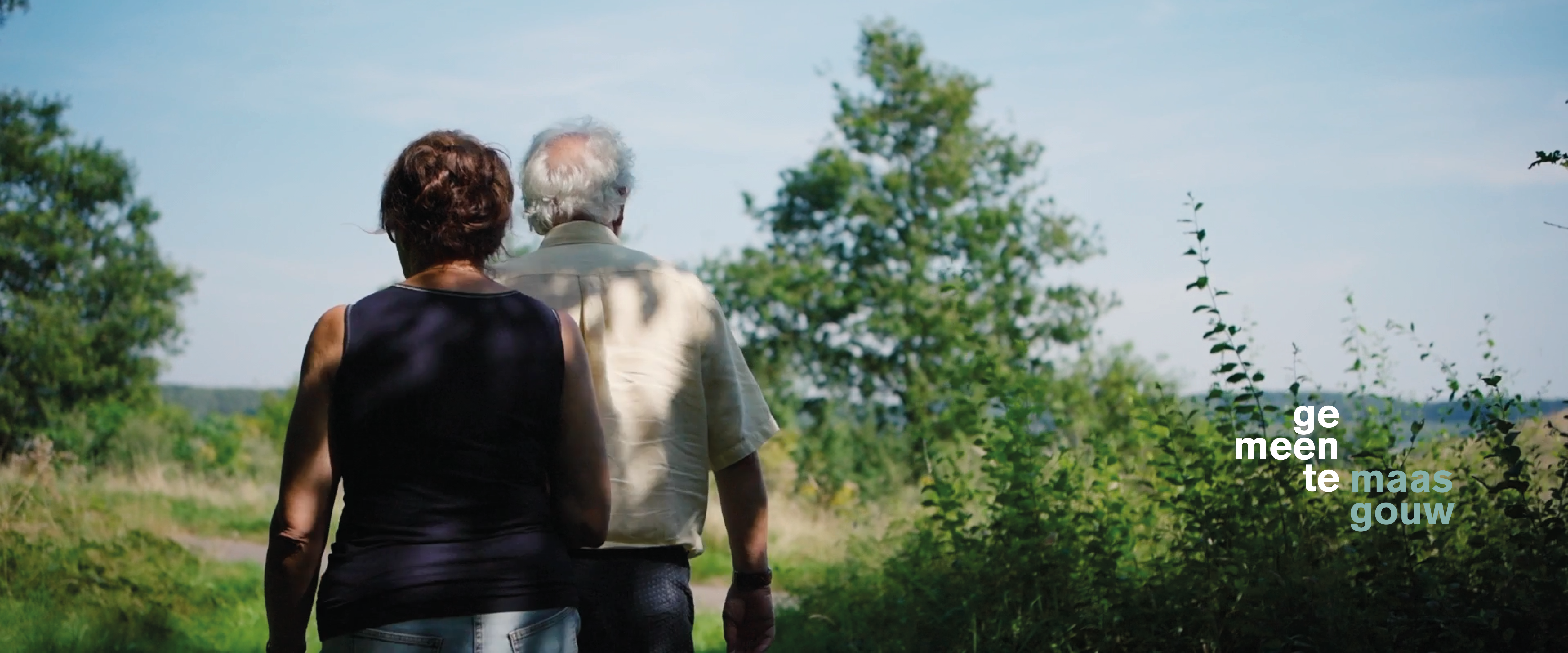 Stel kijkt naar het uitgestrekte landschap van Maasgouw en geniet van de rust en ruimte van deze waterrijke gemeente.