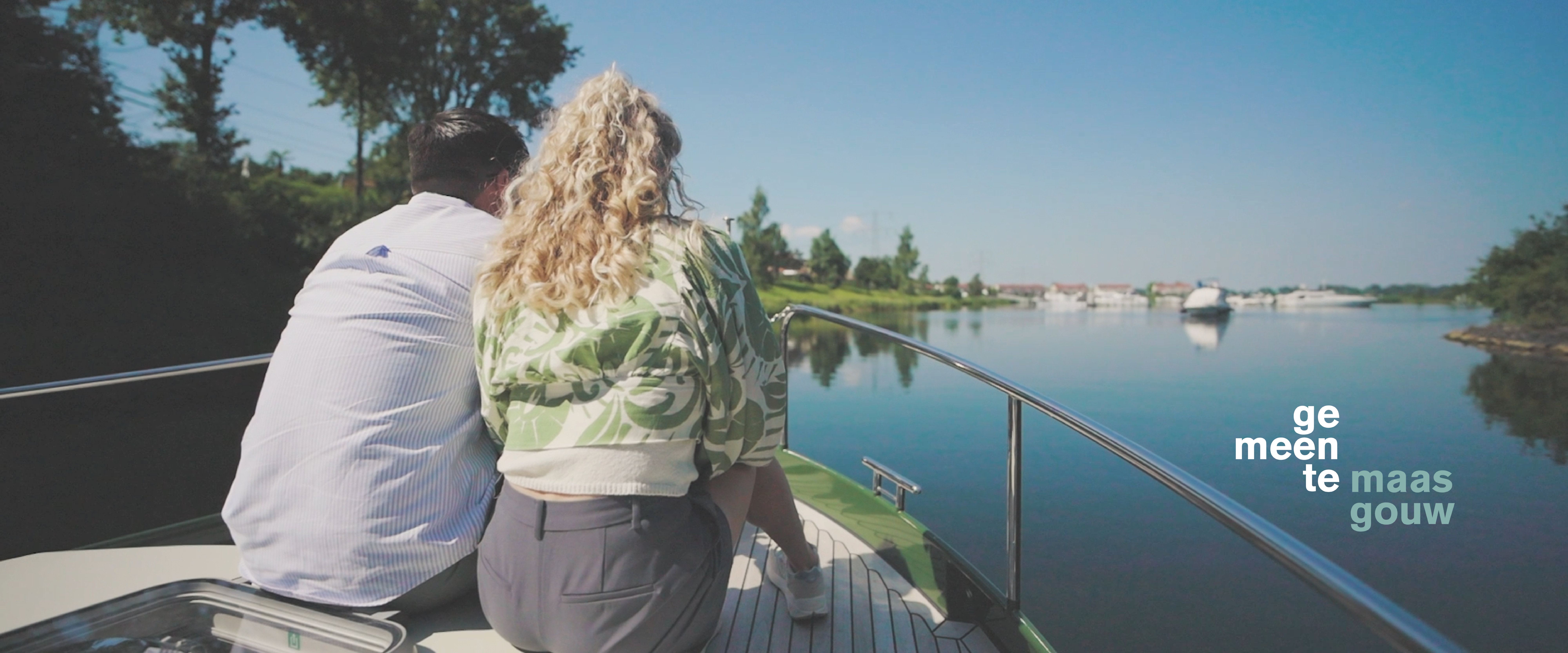 Koppel zit op het voorsteven van een luxe jacht die vaart op de Maasplassen in de gemeente Maasgouw
