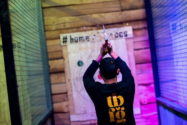 Ein Mann bereitet sich darauf vor, eine Axt auf eine hölzerne Zielwand im Home of Heroes in Buggenum zu werfen.